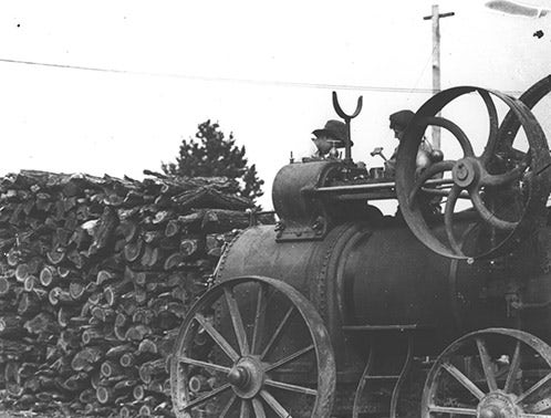 Steam traction engine next to a wood pile - two students working on the engine [Hawkesbury Agricultural College (HAC)] c.1900 (P529)