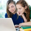 Teen Girls Smiling and Looking at Laptop