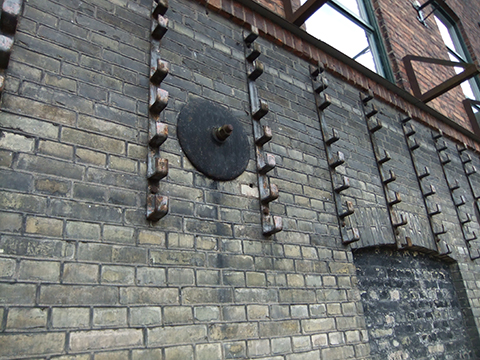 Grey brick wall with artwork of metal hooks and circle feature.