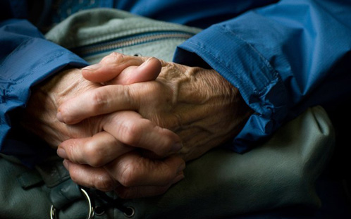 Elderly person clasping hands
