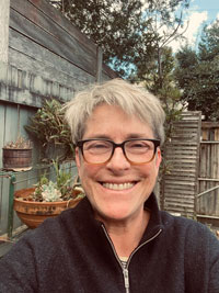 portrait photograph of a white woman with short hair wearing glasses