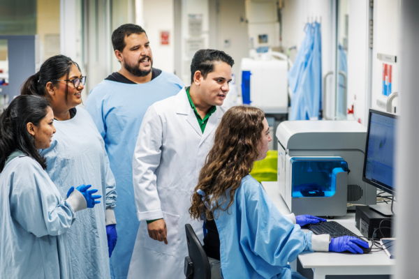A group of researchers from the GutBiotics Lab looking at a screen in the lab