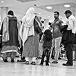Black and white thumbnail of people standing at an airport.
