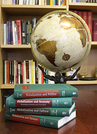 Four volumes of Central Currents in Globalization on a table with a globe positioned behind them.