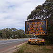 A sign on the side of a road reads 'Planned burns reduce fire risk'.