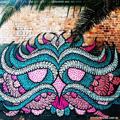A mural from the Street Art Walk - a pink, turquoise and white patterned painting on a brick wall.