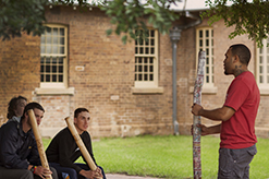 Aboriginal man and students outside with indigenous musical instruments