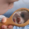 A child looking into a hand mirror