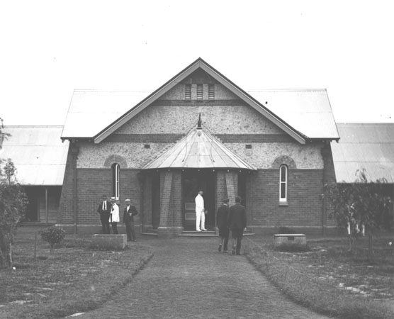 Quadrangle - Men standing outside the Dining Hall - the paths have been made and trees planted [Hawkesbury Agricultural College (HAC)]