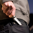 A close-up photo of a young man's hand pulling a knife out of his pocket.