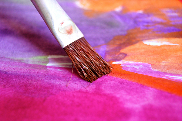 A brush painting bright colours on paper. Image by Uwe Baumann from Pixabay.