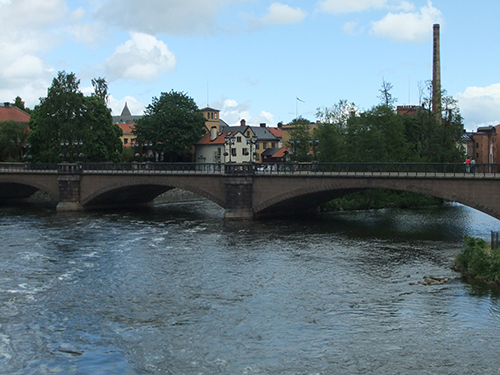The Motala River with a bridge over it and trees and houses behind.