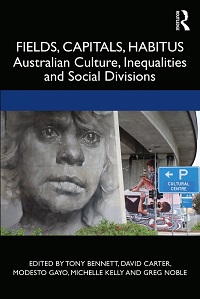 Cover of a book titled ‘Fields, Capitals, Habitus’. A wide horizontal band across the middle of the black cover shows the photograph of an underpass. There is graffiti on the pylons, including a large, close-up image of a face looking off into the distance. A blue sign indicates the location of parking for the ‘Cultural Centre’. The book’s title is above the photograph. It is ‘Fields, Capitals, Habitus’, and the subtitle is ‘Australian Culture, Inequalities and Social Divisions’. Below the photo are the words ‘Edited by Tony Bennett, David Carter, Modesto Gayo, Michelle Kelly and Greg Noble’. The Routledge logo is in the upper right hand corner of the cover.