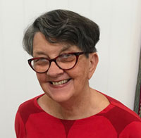 Portrait photograph of a woman with short dark-grey hair wearing glasses