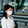 An Asian girl with a white mask over her nose and mouth.