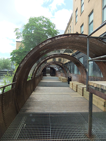 A walkway beside a building with sections of it enclosed like a tunnel.