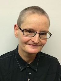 Portrait photograph of a woman with very short hair and glasses