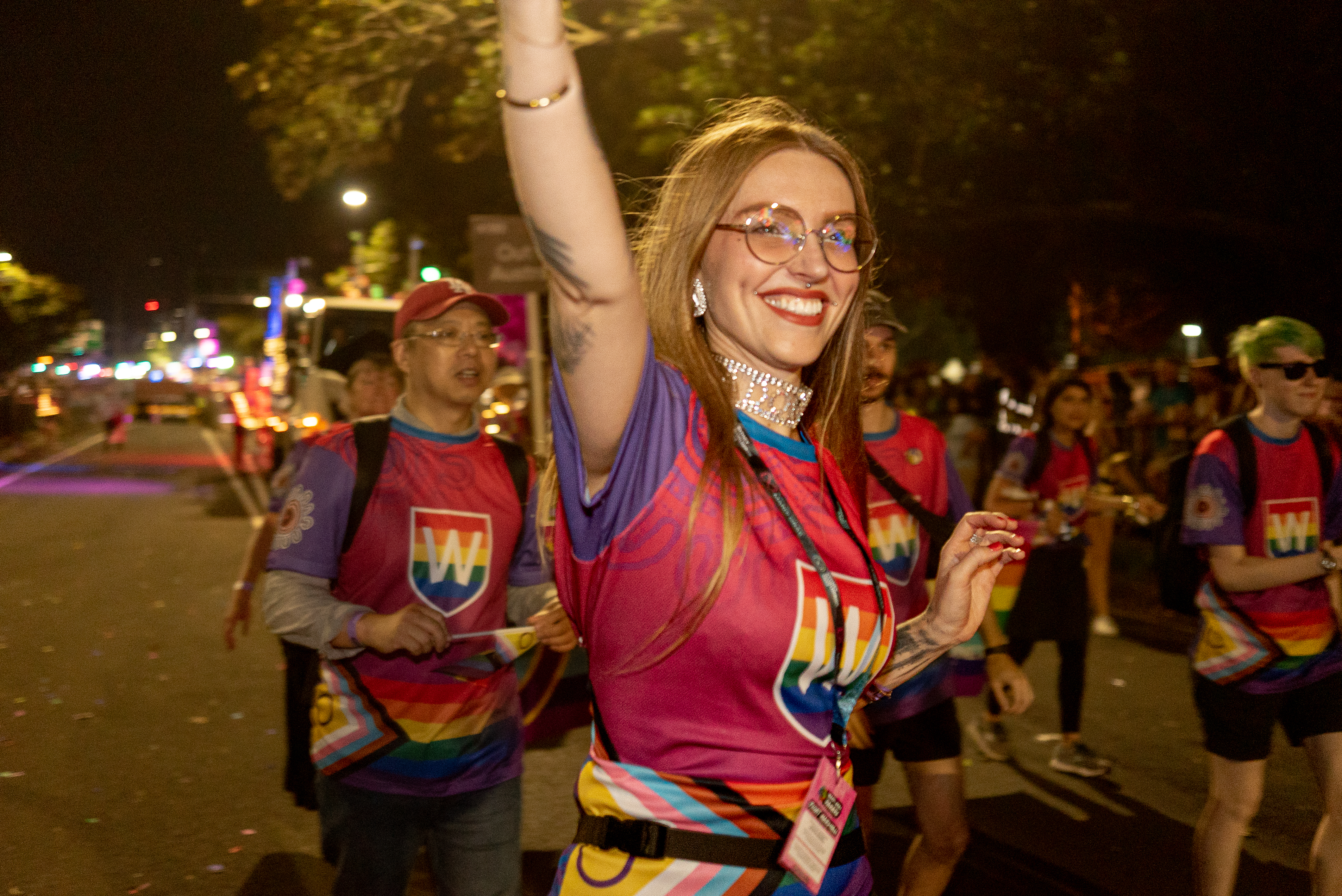 WSU Mardi Gras participants marching in the parade with one woman smiling and raising her arm in celebration