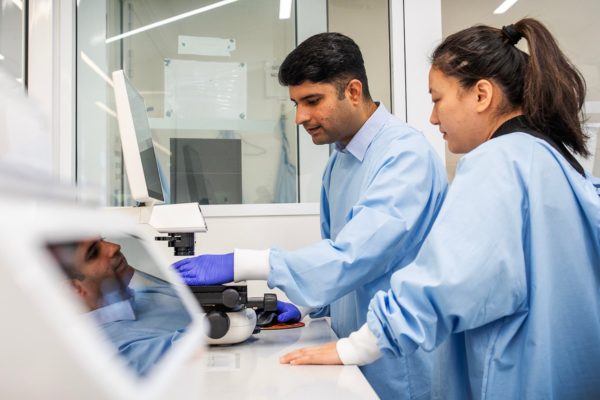 Two researchers in lab coats looking at a screen