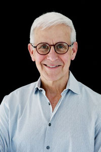 Portrait photograph of a man with white hair and glasses