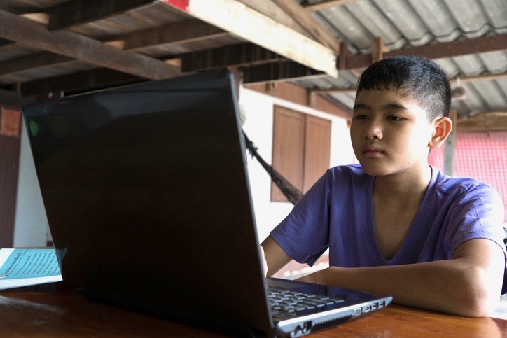 Boy sitting at table using laptop in Thailand Boy sitting at table using laptop in Thailand