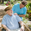 Elderly man in a wheel chair being cared for by a male nurse
