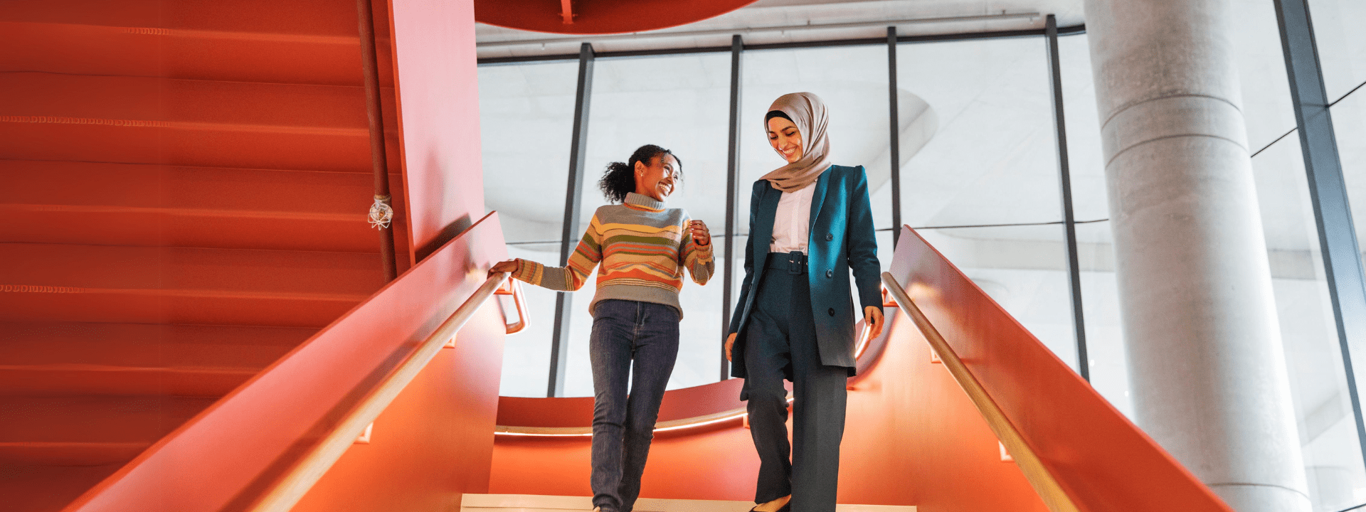 Two female students are walking down the stairs together
