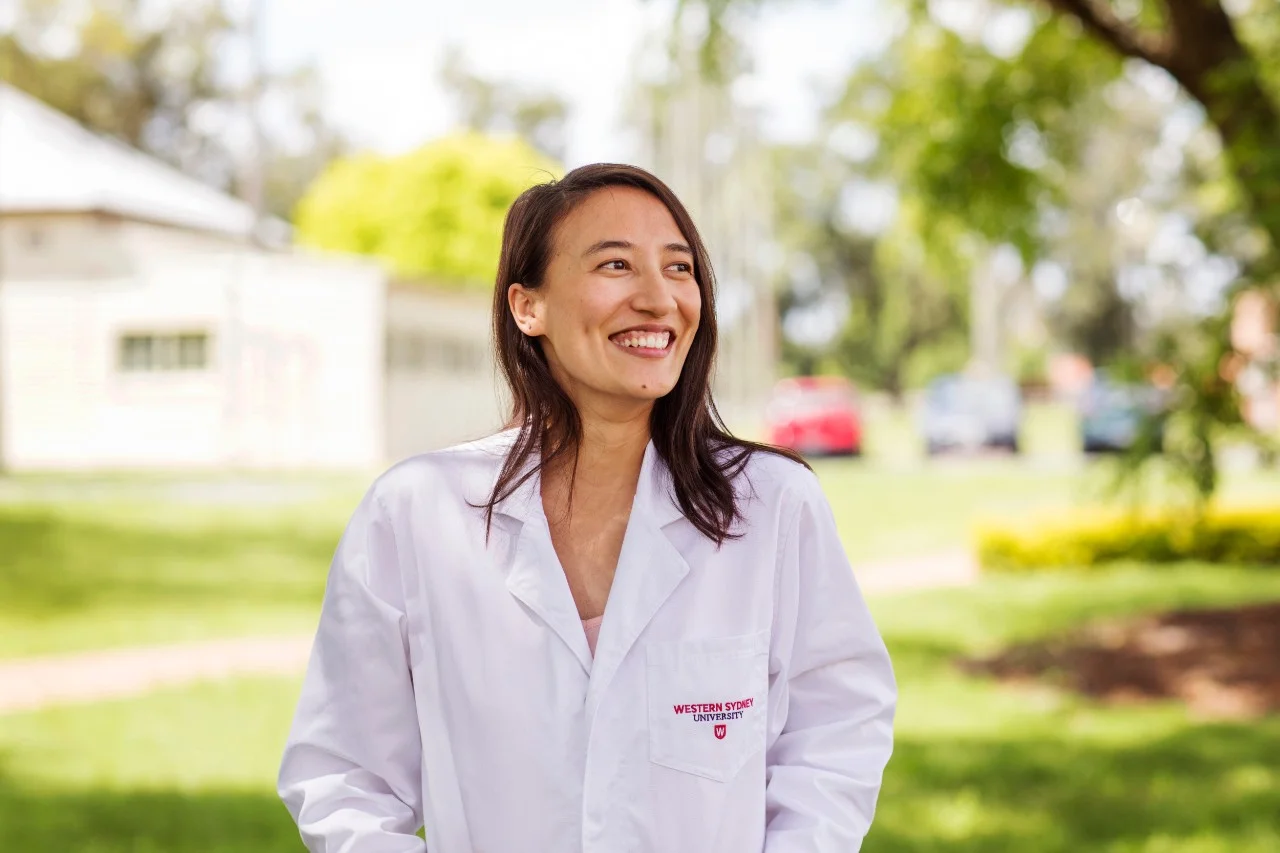 Western Sydney University researcher smiling on campus and wearing a lab coat