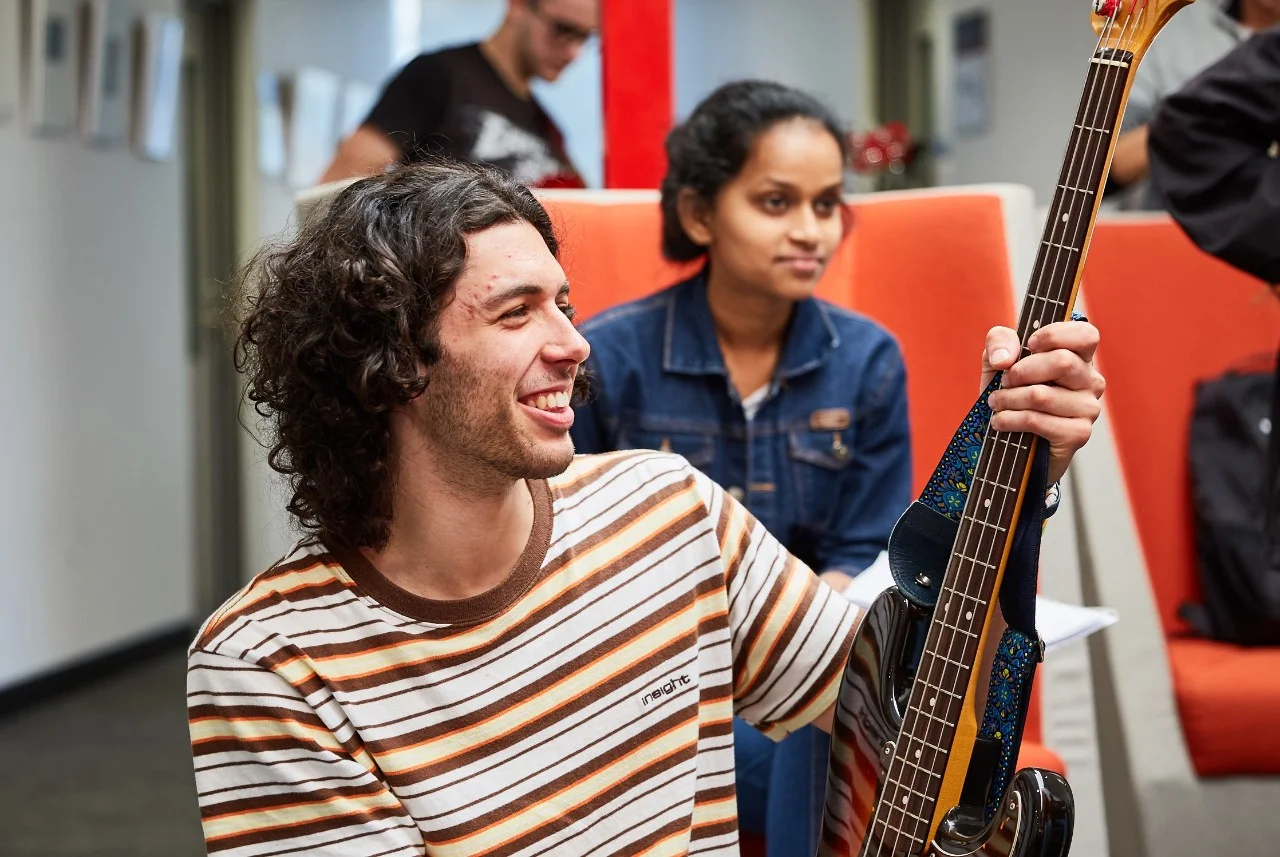 Male music student holding a guitar