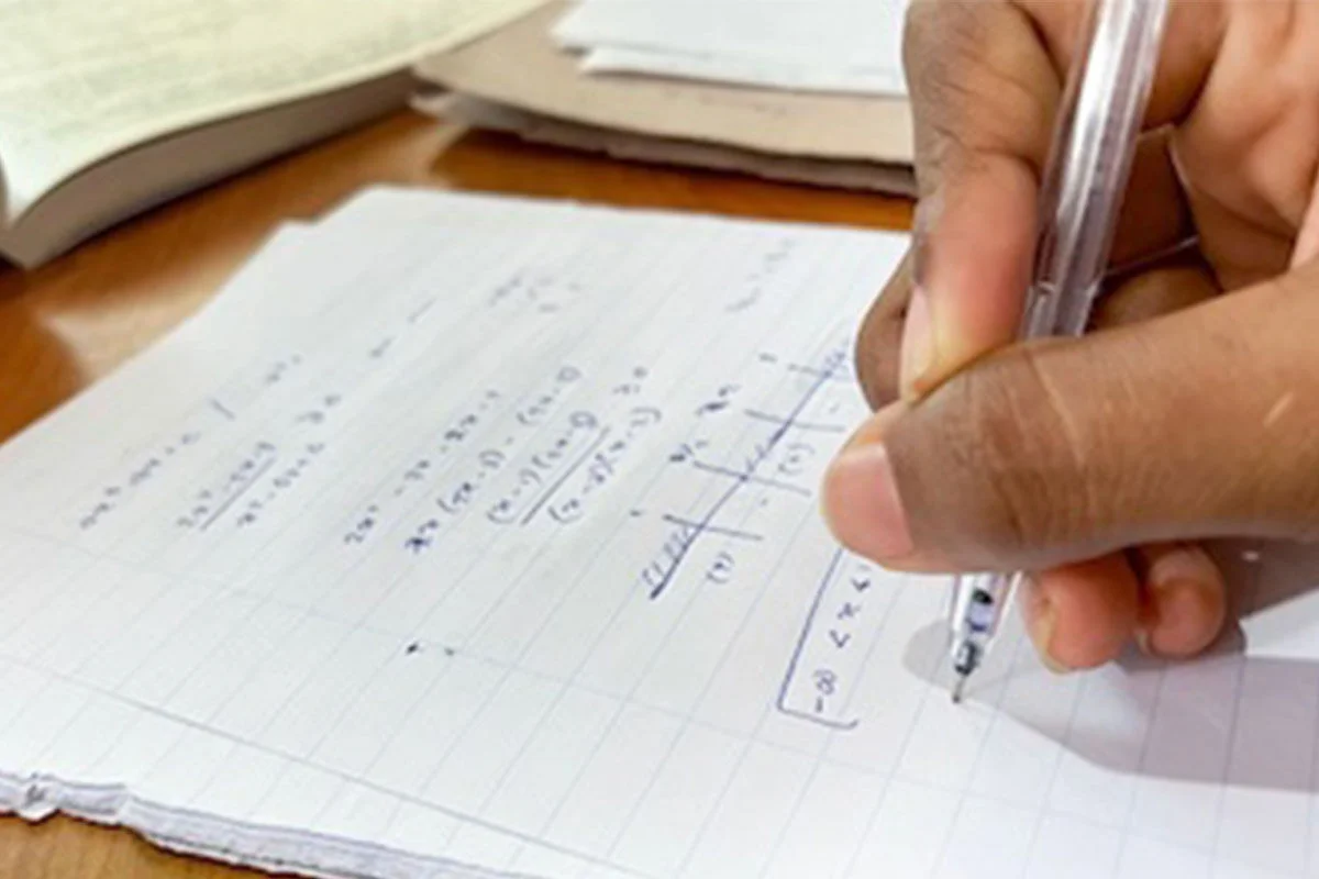 student writing text on paper with a pen