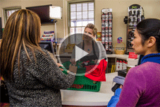 Video - Play button over picture of two women experiencing racism from a shop assistant.