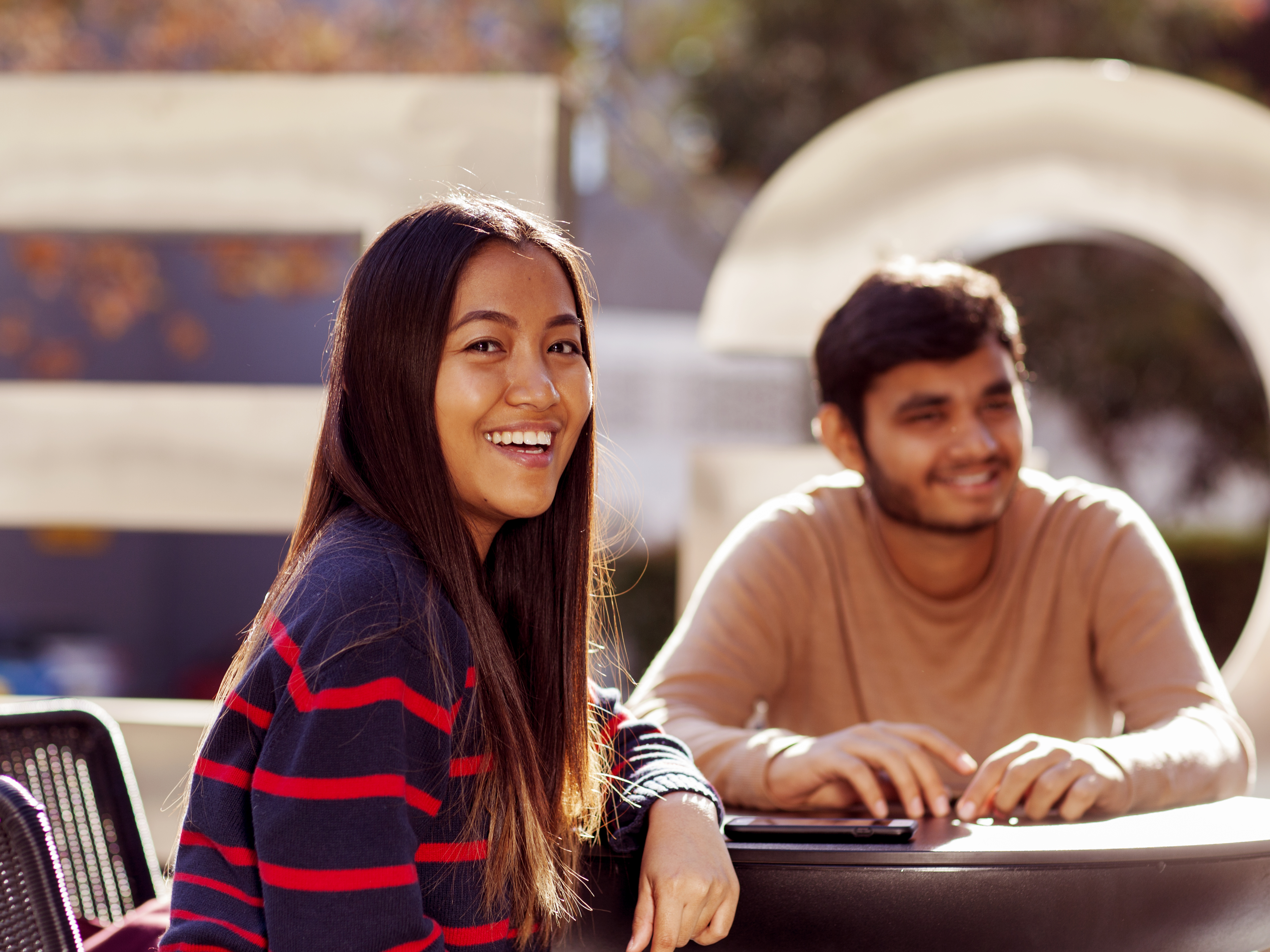 Female and male students sitting outdoors at 100 George St, Parramatta