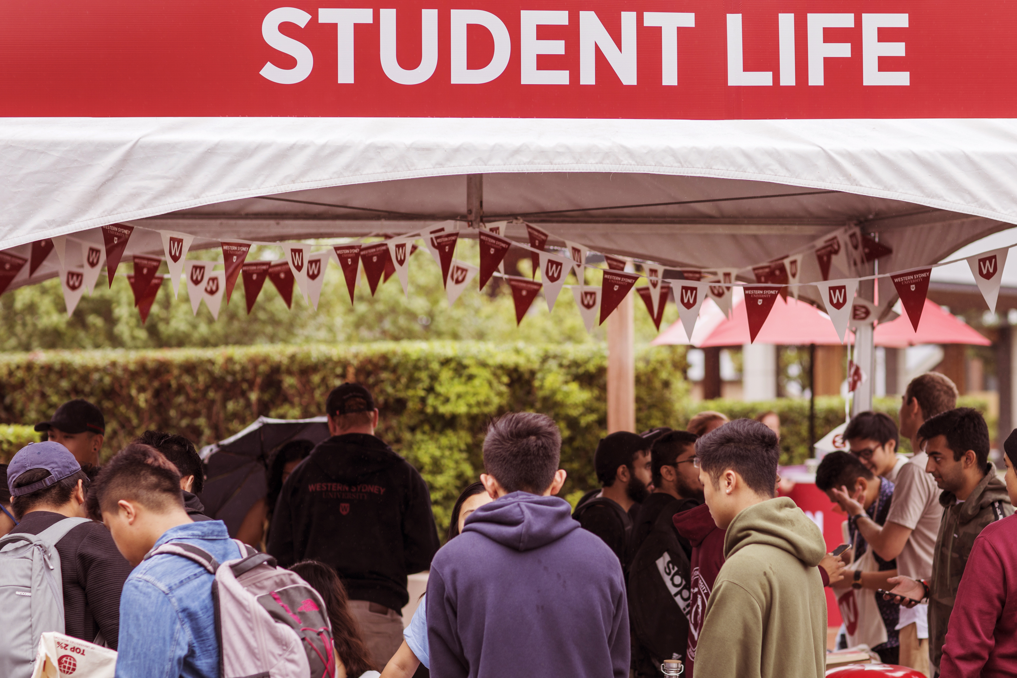 Student life sign with students on campus