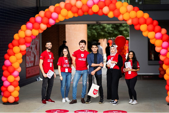 Group of students at welcome week under arch of balloons