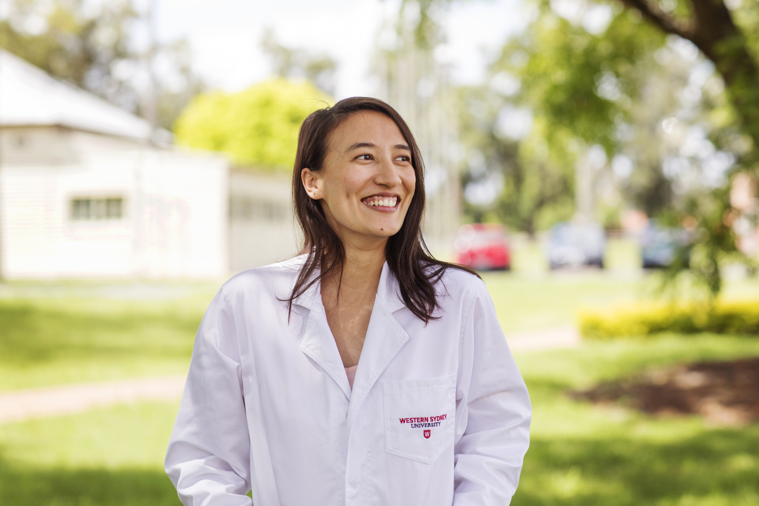 Western Sydney University researcher smiling on campus and wearing a lab coat