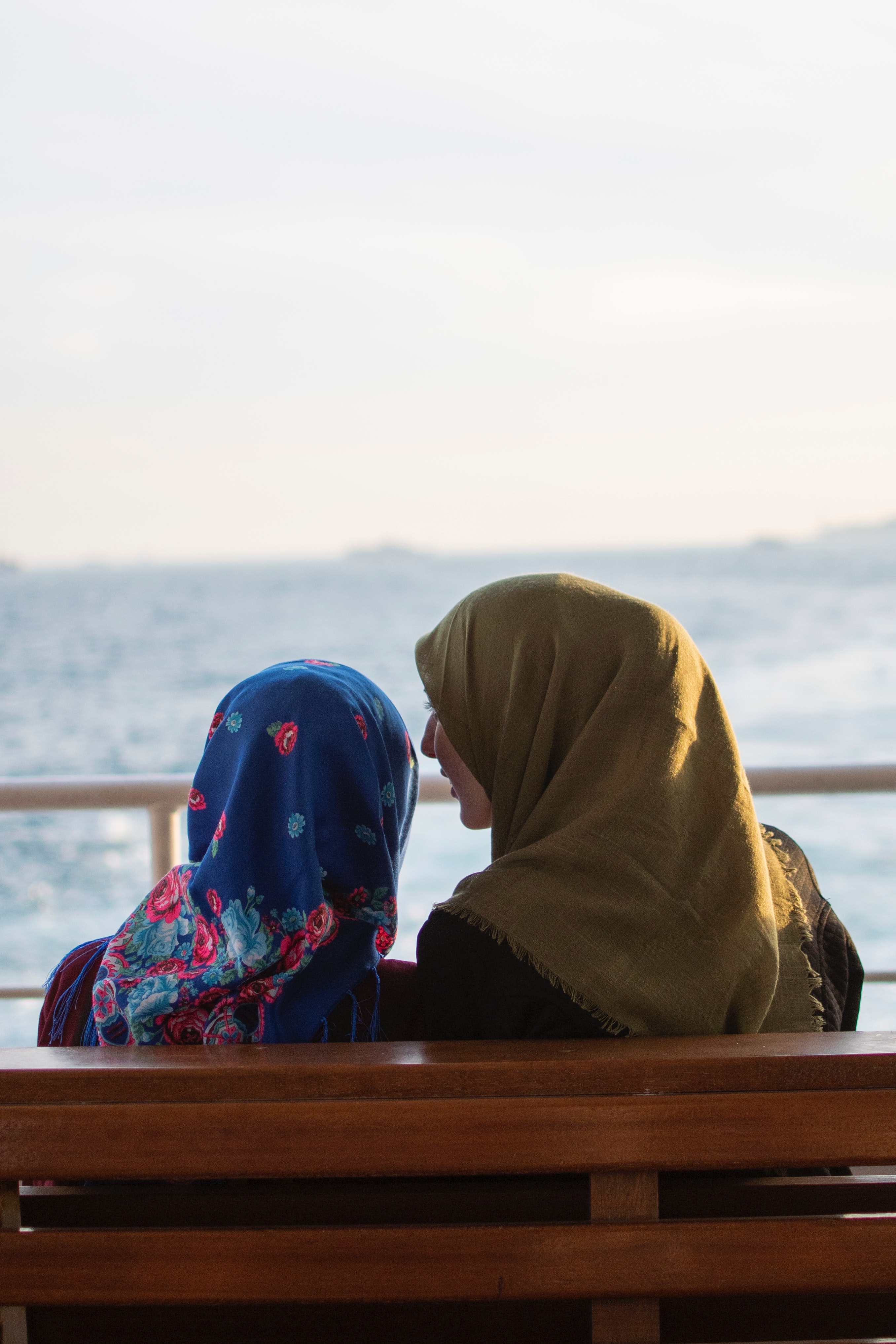 Muslim women sitting next to the beach