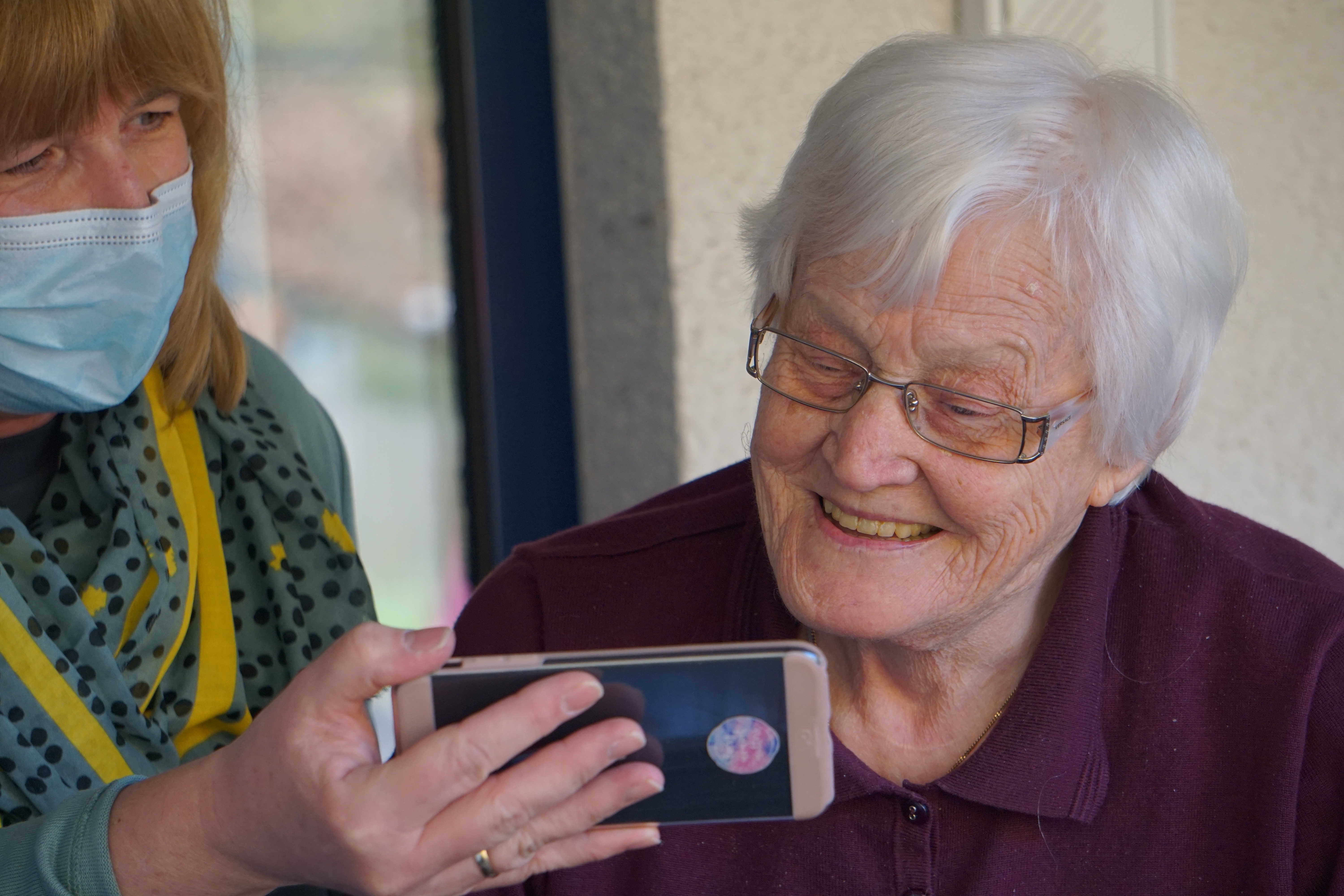 Aged care nurse with elderly person using a smartphone