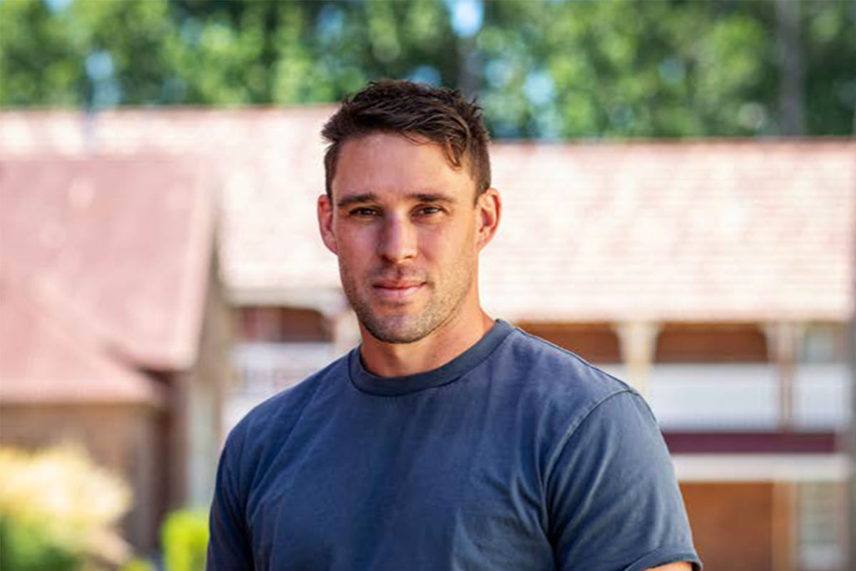 Aaron Spiteri standing outside wearing a blue shirt facing the camera