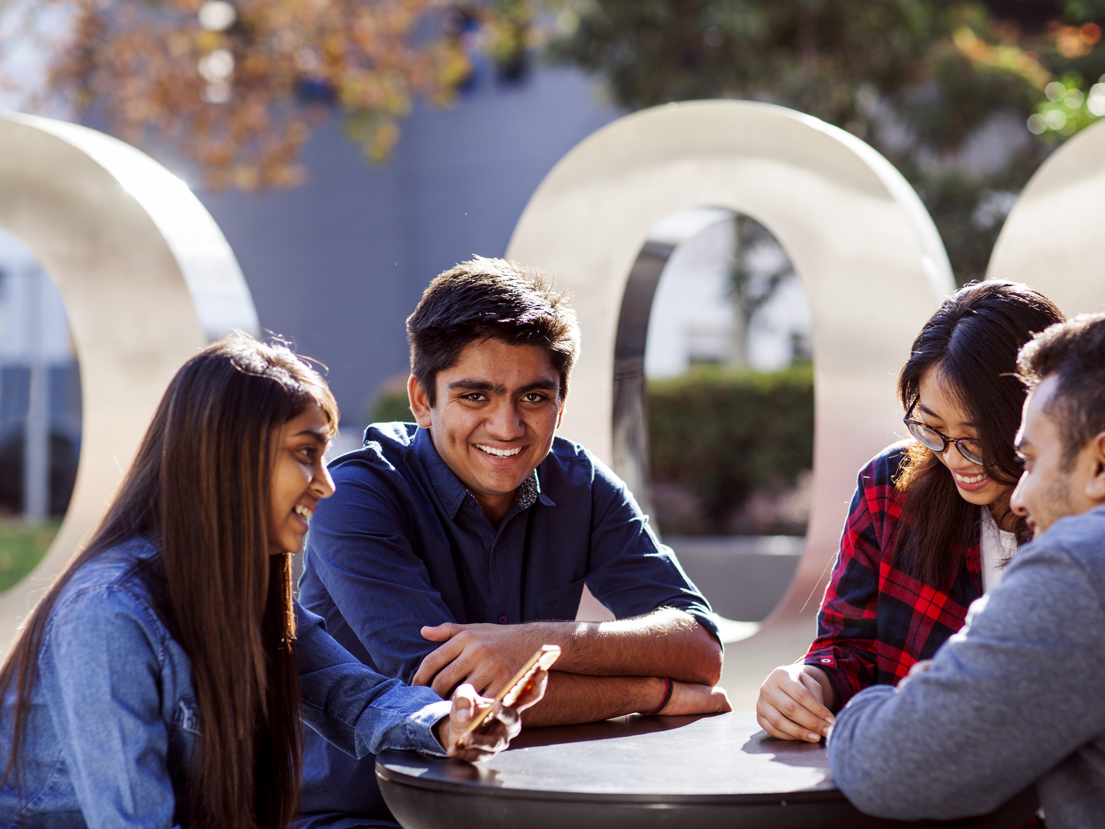 Group of four students sitting together on campus