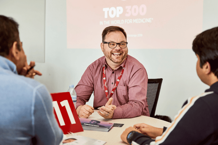 Our People thumbnail of a group of professionals having a conversation.