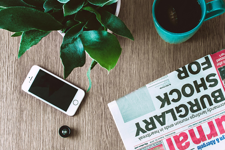 Smartphone, newspaper and coffee on desk