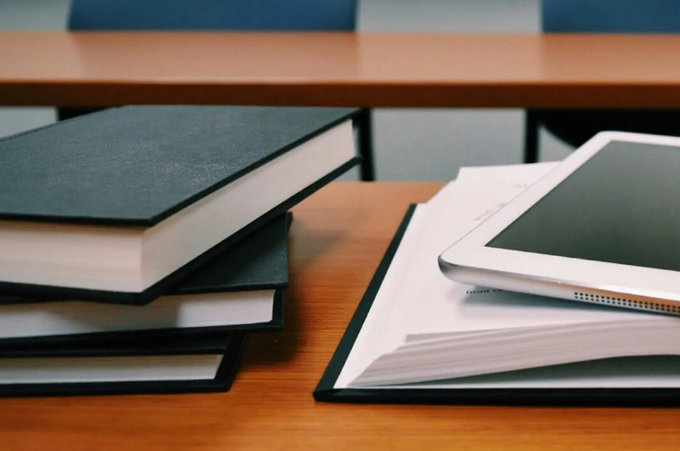 Stack of books and tablet in classroom