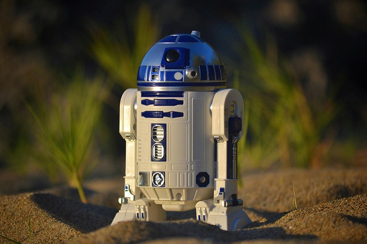 R2-D2 toy robot standing in sand dunes