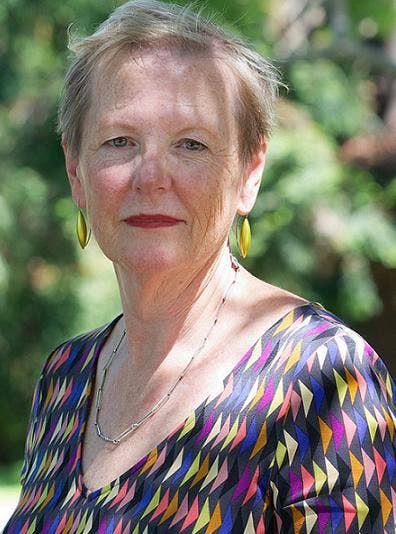 Shoulder-up photo of Katherine Gibson wearing a colourful top, against blurred trees