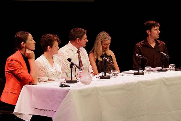 Keith sitting at a white table with four other panelists, three women and 1 man