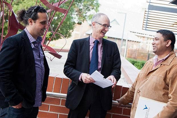 Three men standing together laughing