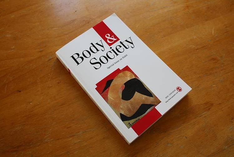 A white book called Body and Society placed on a wooden bench