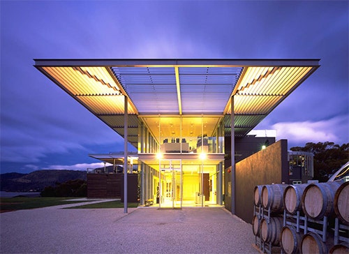 The Museum of Old and New Art at night. The building is lit brightly in the purple dusk.