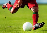Shows the legs of a soccer player who is about to kick a soccer ball.