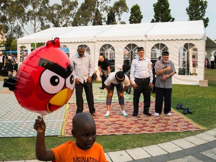 Four men standing on a carpet with a little boy holding a balloon